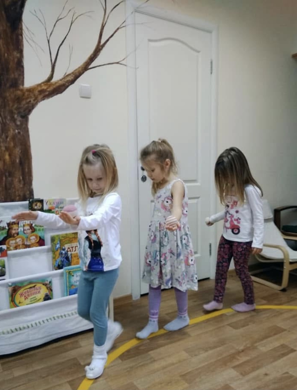 Group of children doing a Montessori walking on the line lesson, carrying objects and moving carefully around the classroom without contact