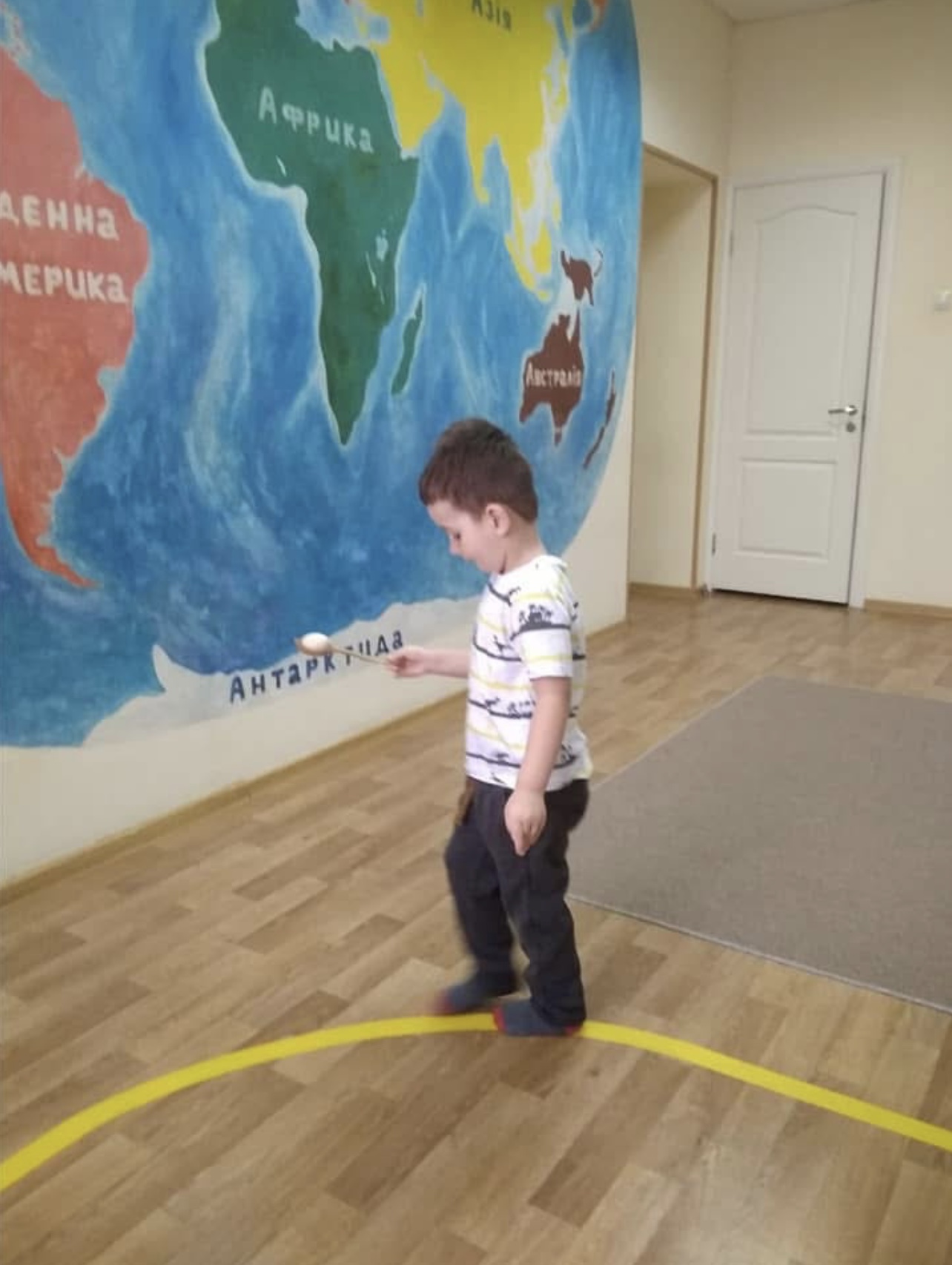 Child practicing a Montessori balance exercise by walking on a taped line on the floor, focusing on coordination and control