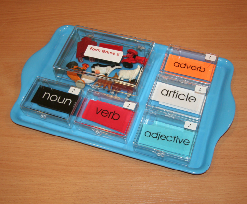 Montessori Phonetic Farm Game with Adverb – Includes miniature phonetic objects and color-coded laminated grammar cards for noun, verb, adjective, article, and adverb, arranged in clear boxes with black tray.